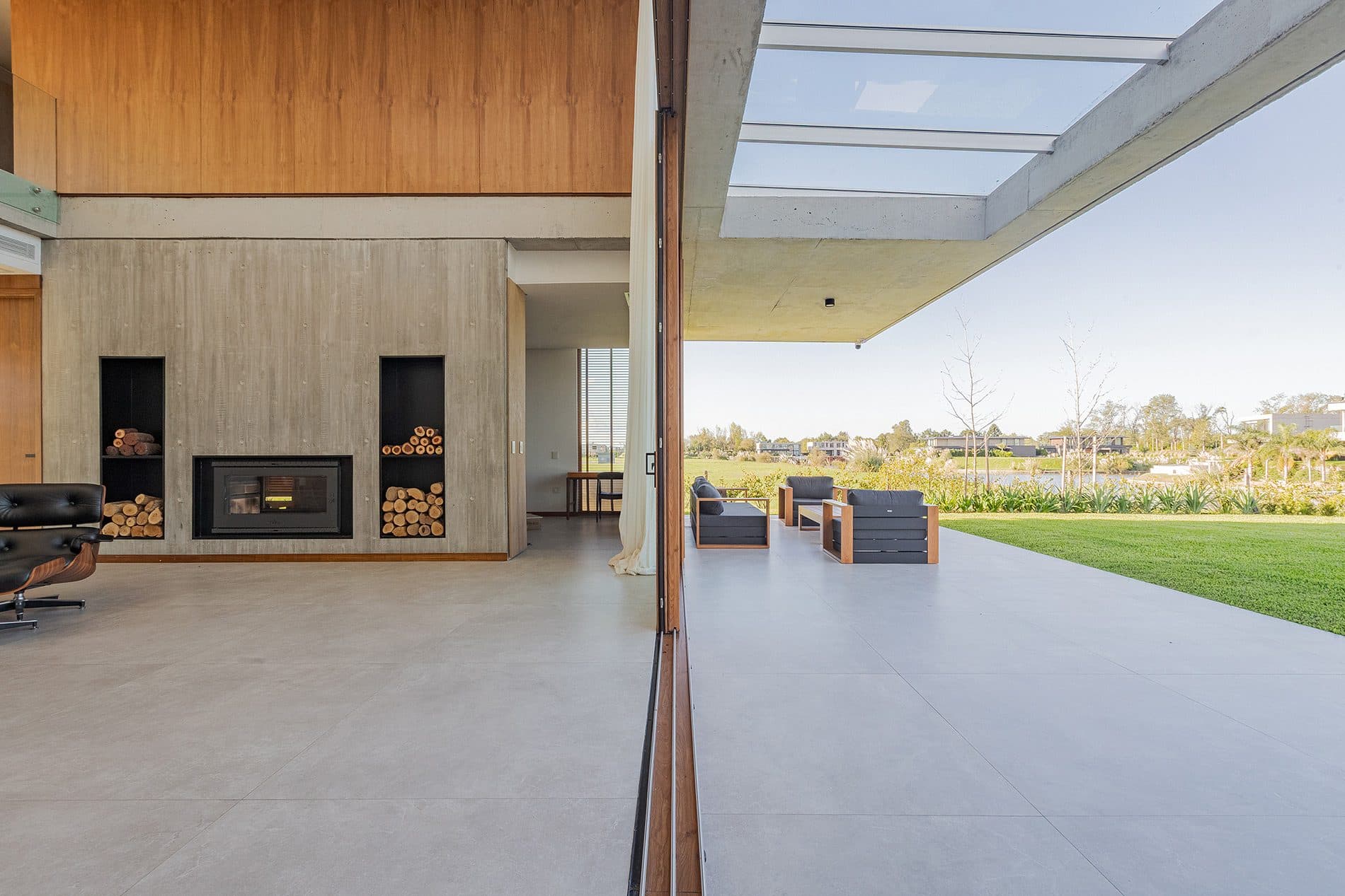 Galería abierta con mesa de madera, chimenea y vista al jardín