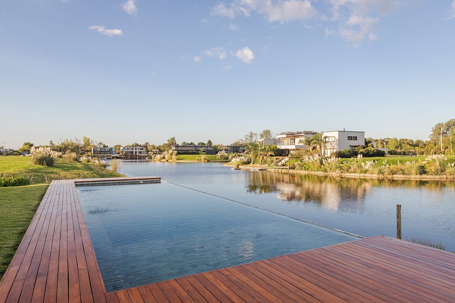Deck de madera y piscina que se funde con la laguna